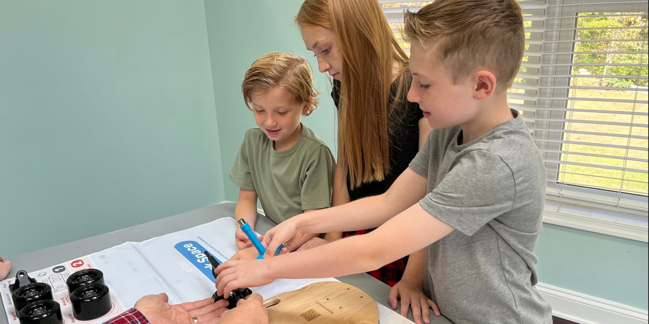 A father assembling Elos DIY skateboard kit on a Sunday morning with his three kids for engaging and educational family quality time