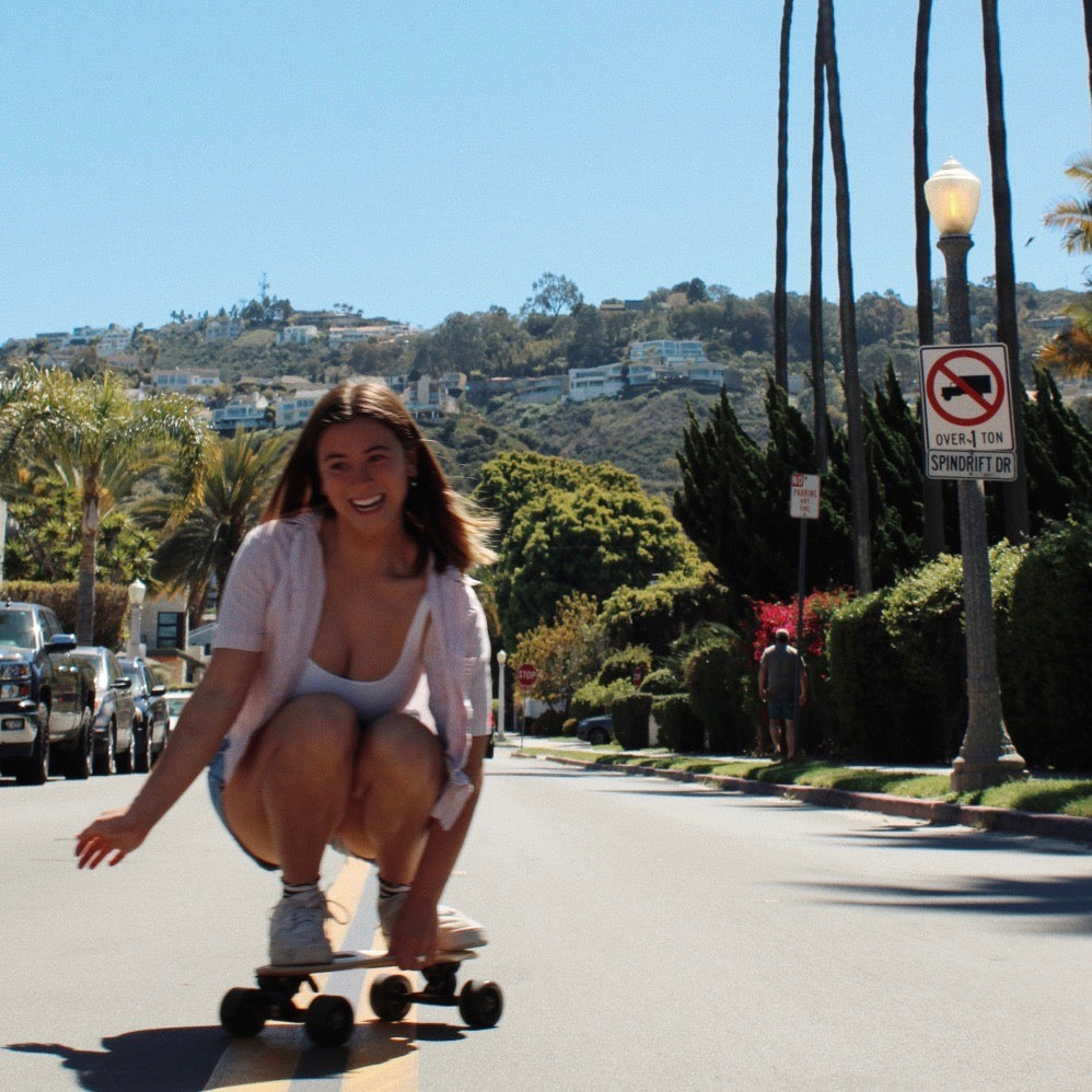 A girl cruises down a typical California street, surrounded by palm trees, on her small skateboard. The compact design of the skateboard, commonly referred to as a "skateboards small", provides a smooth and easy ride for cruising on streets and sidewalks.