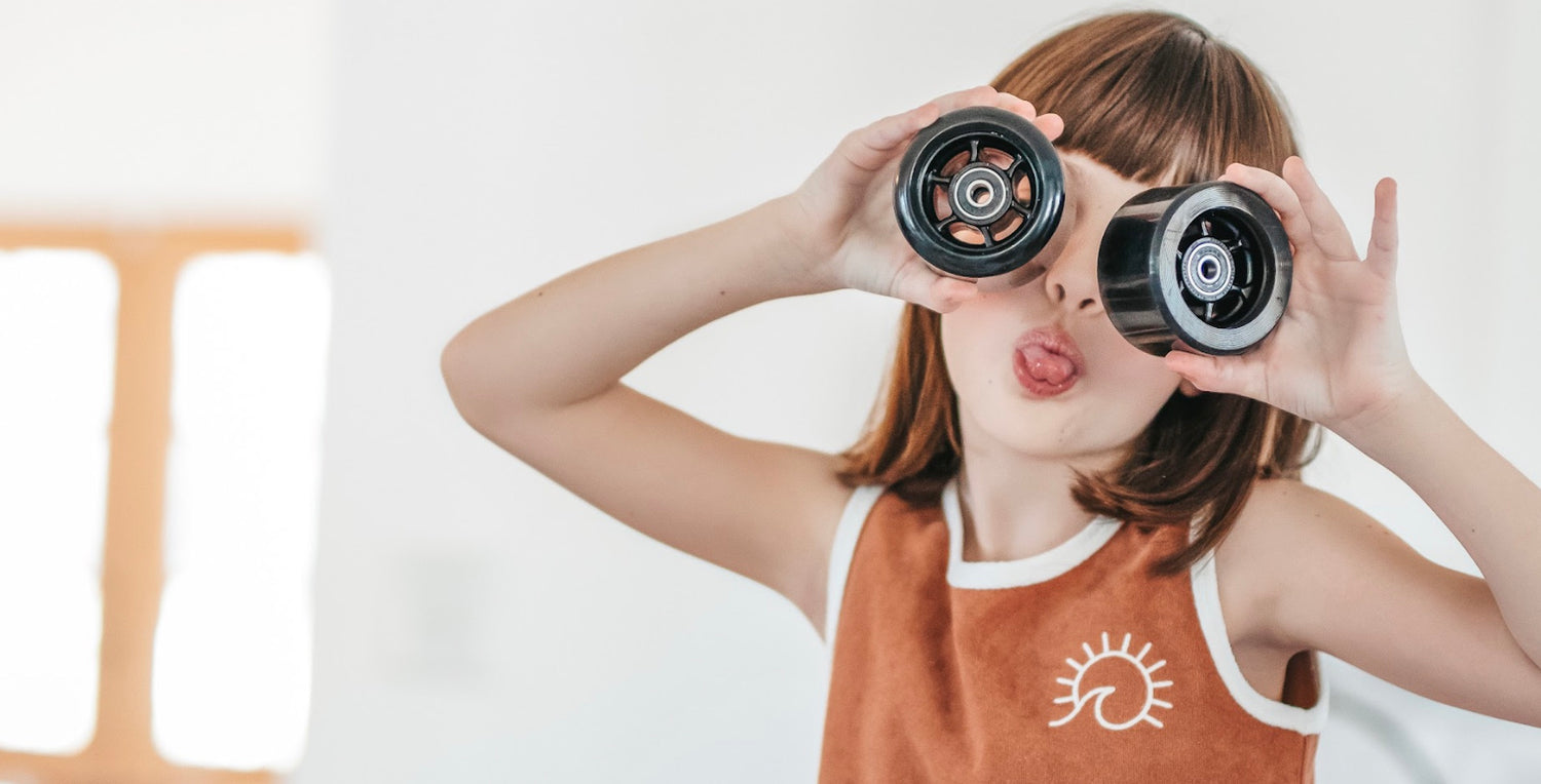 A little girl is holding two Elos lightweight wheels while making a mischievous face