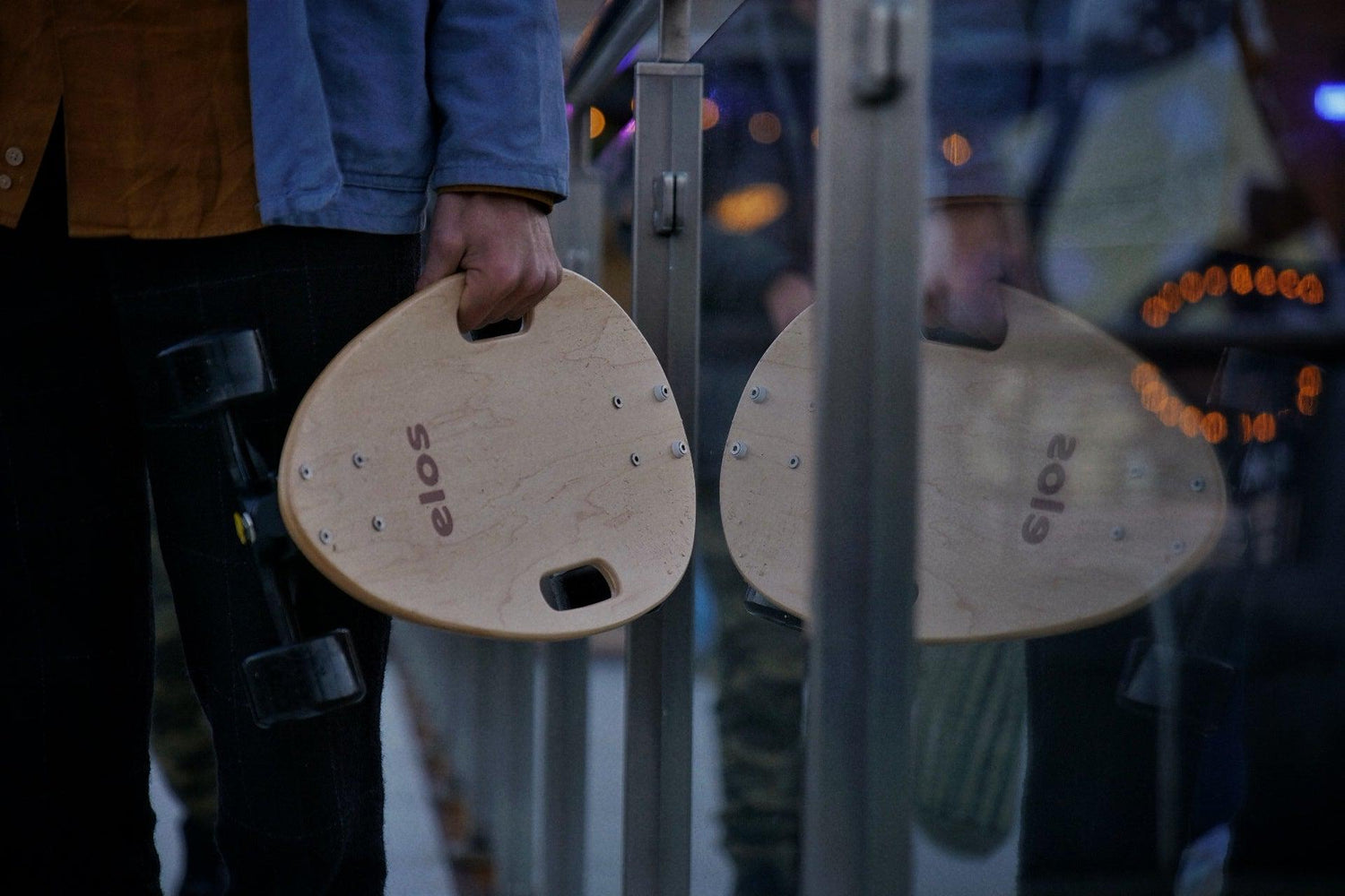 A man is holding Elos mini skateboard in his hand in the street of London