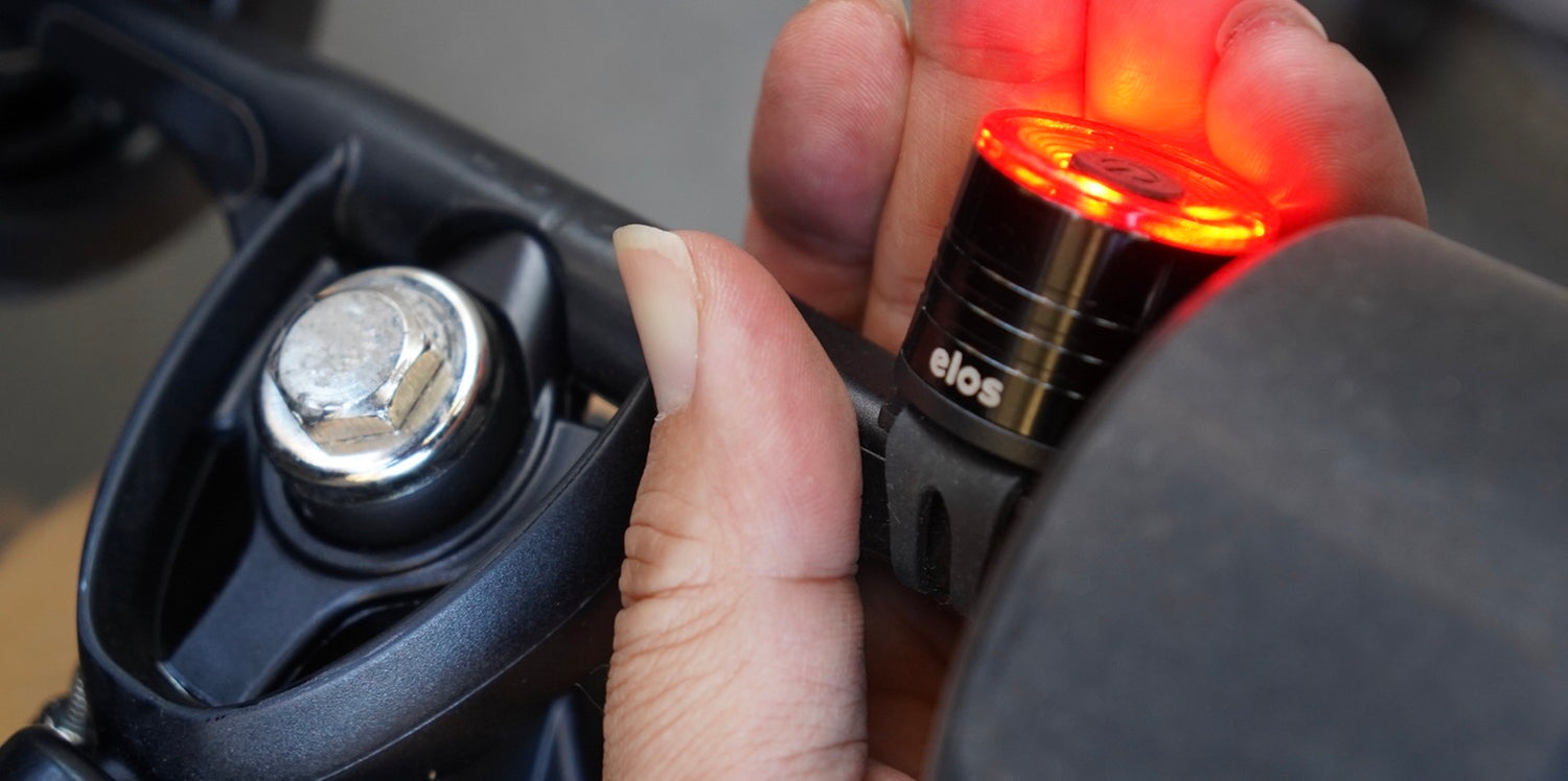 A man is holding Elos trucks to display Elos small, conpact urban safety light attached to the truck