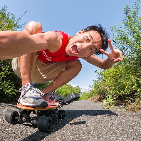 A man riding Elos skateboard in a squatting pose on a sunny day with a happy expression
