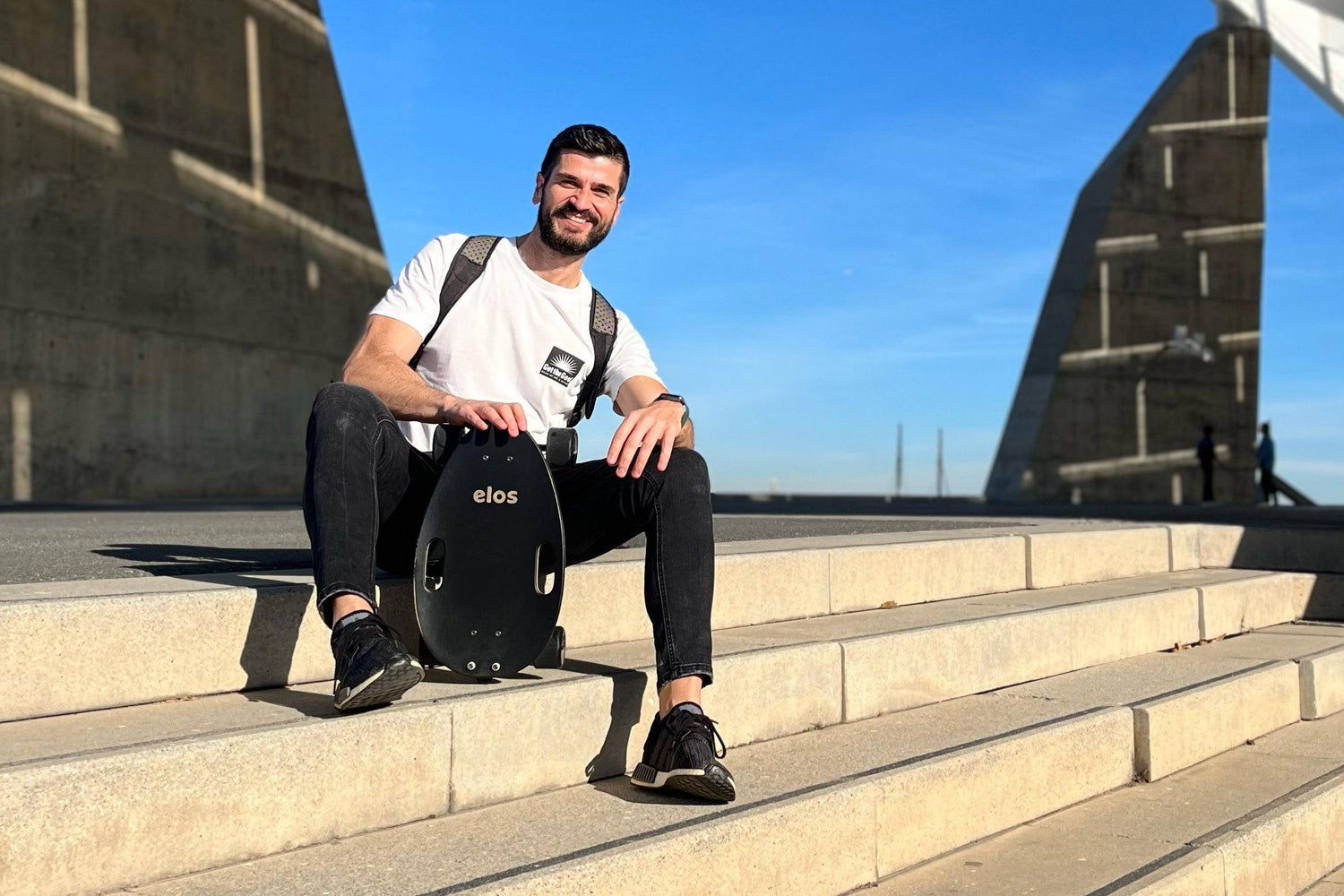 A man sitting on the stairs and holding black Elos on his hand