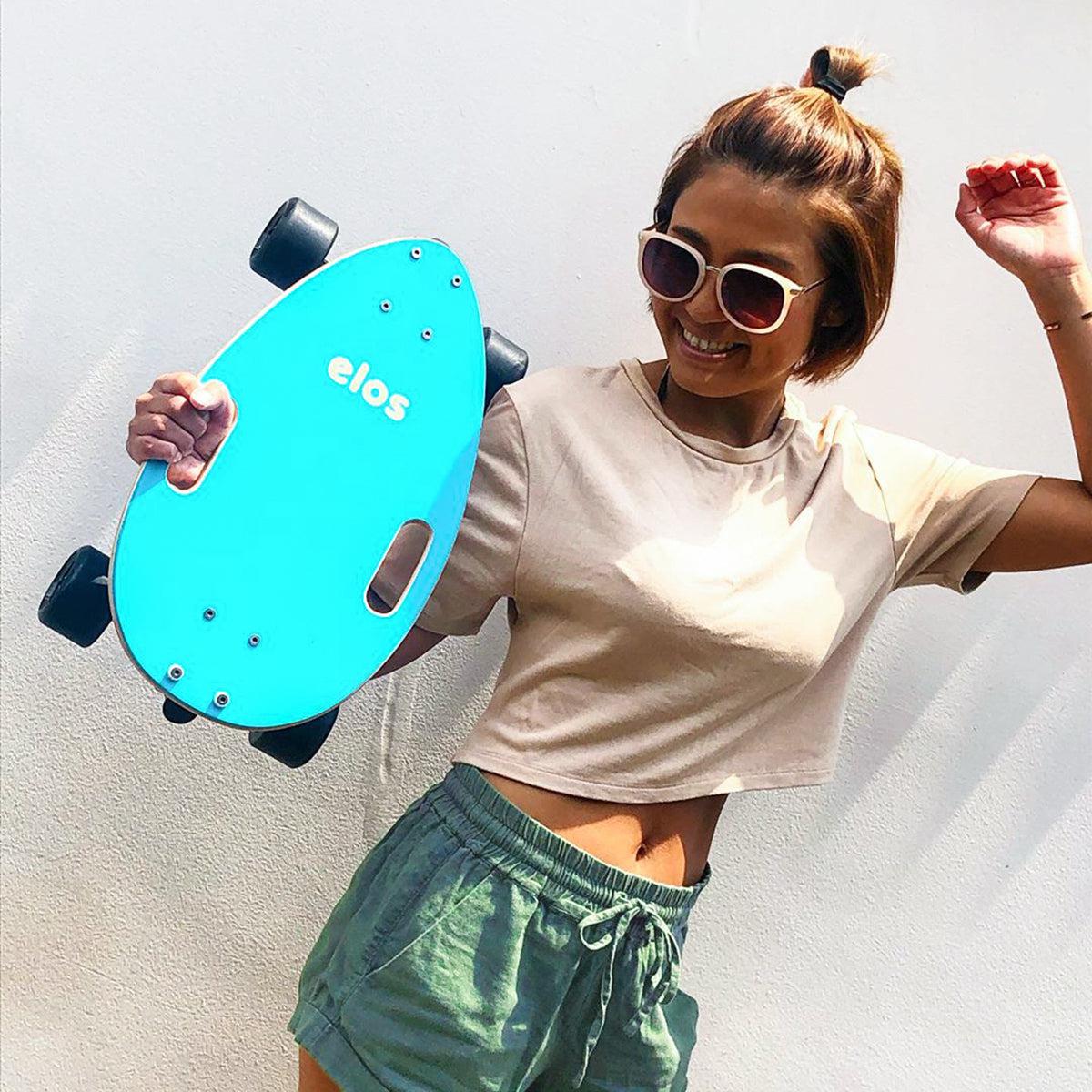 Joyful girl holding Elos skateboardswith a smile