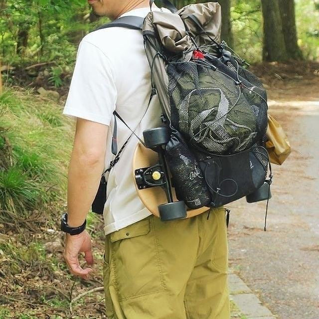 A man attaching Elos skateboards to backpack for added road fun during camping trip with friends