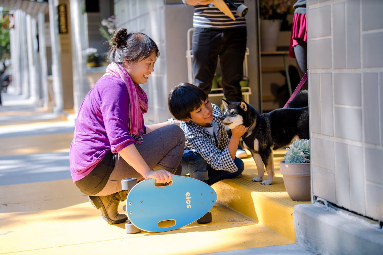 A woman and a boy happily petting Shiba dog with Elos beside them