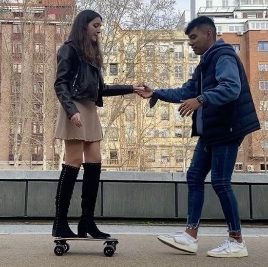A young spanish boy is teaching a young spanish girl how to skate Elos in Madrid