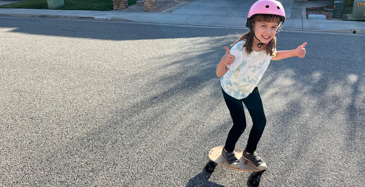 Girl skating on Elos boards outdoors, giving a thumbs-up, showcasing Elos as the best skateboards for kids to begin learning skateboarding