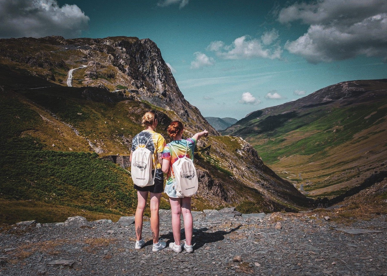 Two girls standing on a mountain with Elos skateboards on their backs